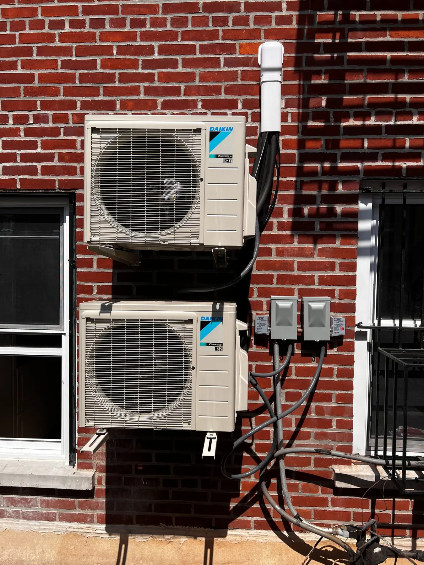 Two outdoor ductless units mounted on a red brick wall