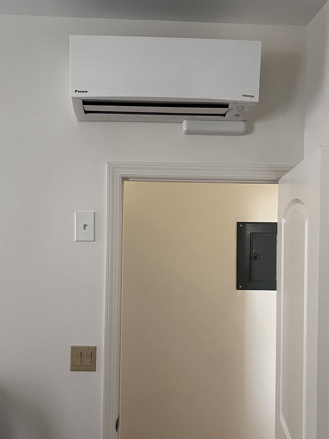 Wall-mounted Daikin indoor unit above a doorway, showing the full unit and air outlet